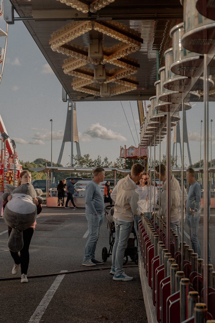 Visitors engage at a vibrant carnival with a ticket booth and rides in view.