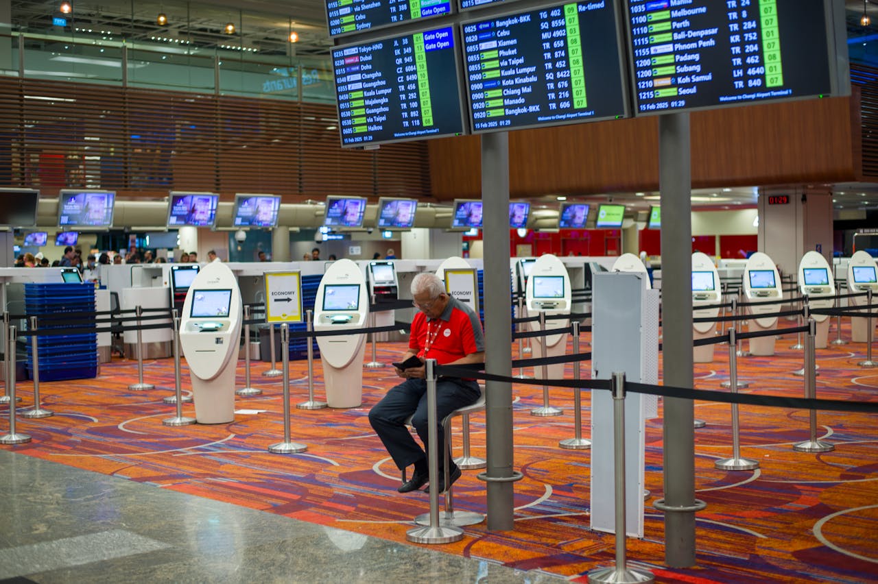 about-01 Busy airport terminal interior with flight information displays and check-in kiosks.